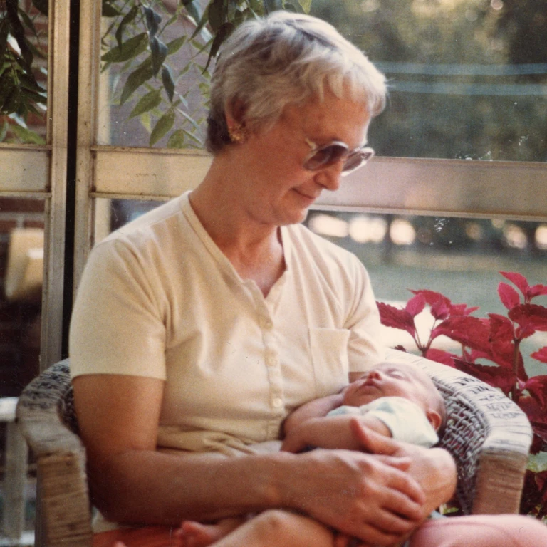 1984 — my grandma holding me in the gazebo, surrounded by plants and summer light.