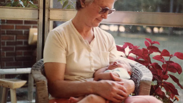 1984 — my grandma holding me in the gazebo, surrounded by plants and summer light.