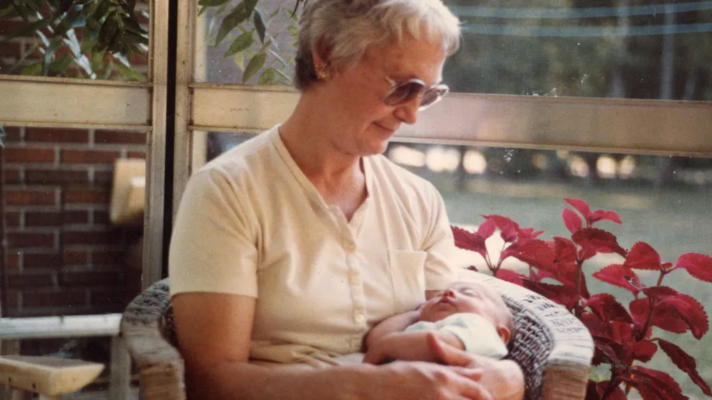 1984 — my grandma holding me in the gazebo, surrounded by plants and summer light.