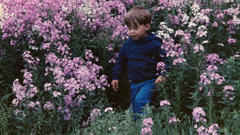 Nolan Franklin as a young child walking through tall pink and white phlox along the old railroad tracks near his grandmother’s house.